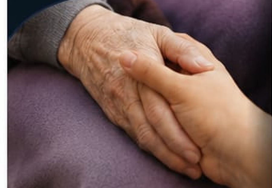 Eine helfende Hand hält die Hand einer älteren Person.